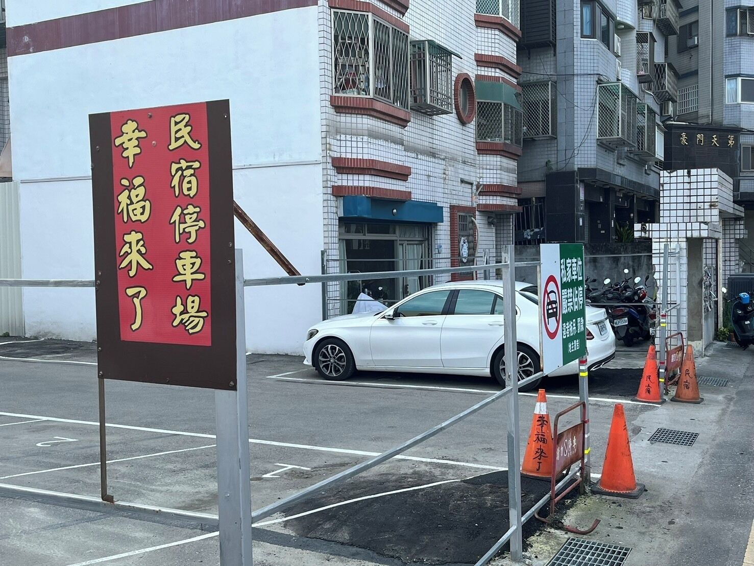 標示幸福來了民宿停車場的戶外車位，旁有住宅與停放車輛。