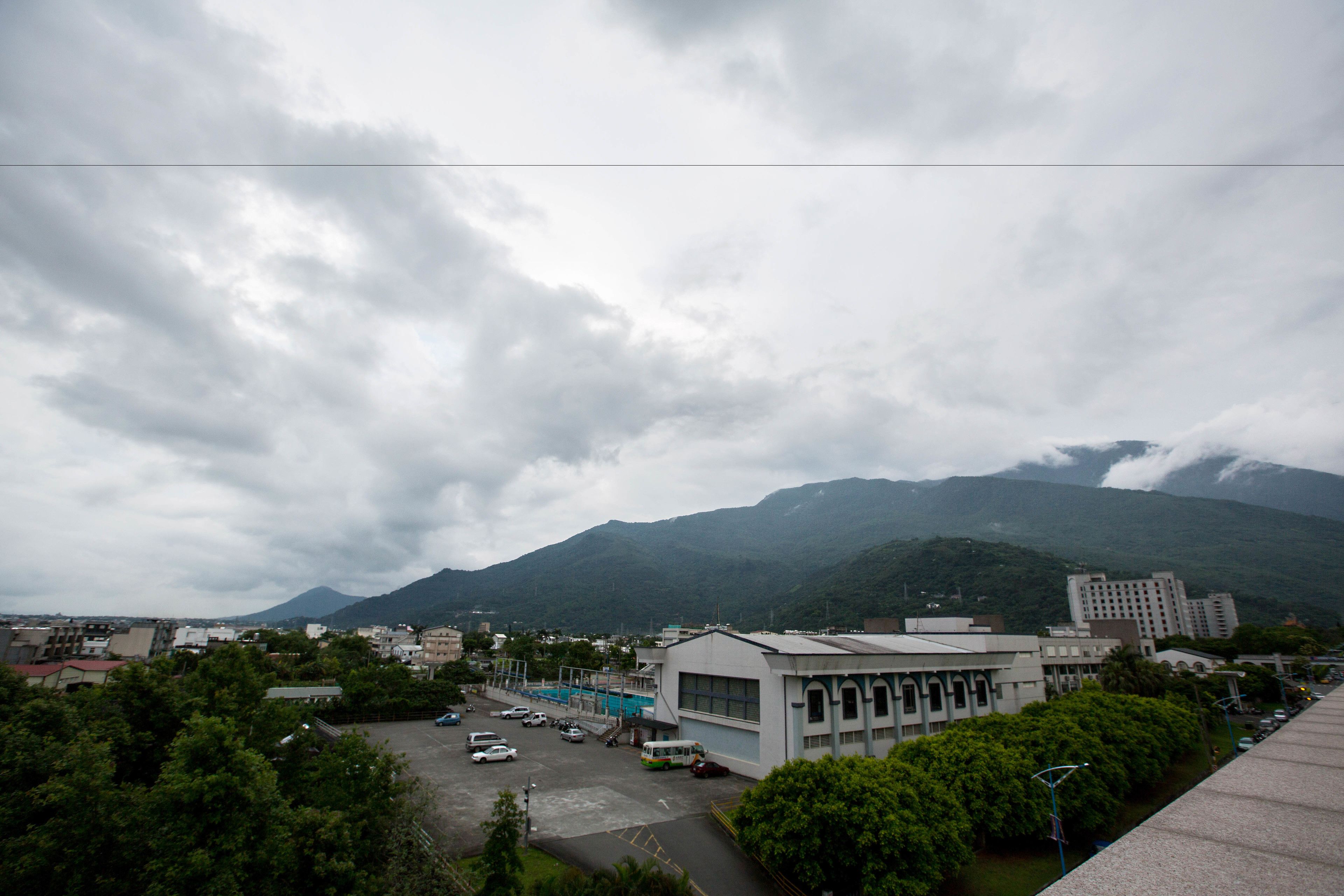 鮭魚歸魚環境照片：近處建物與停車空地，遠處可見雲霧山脈。