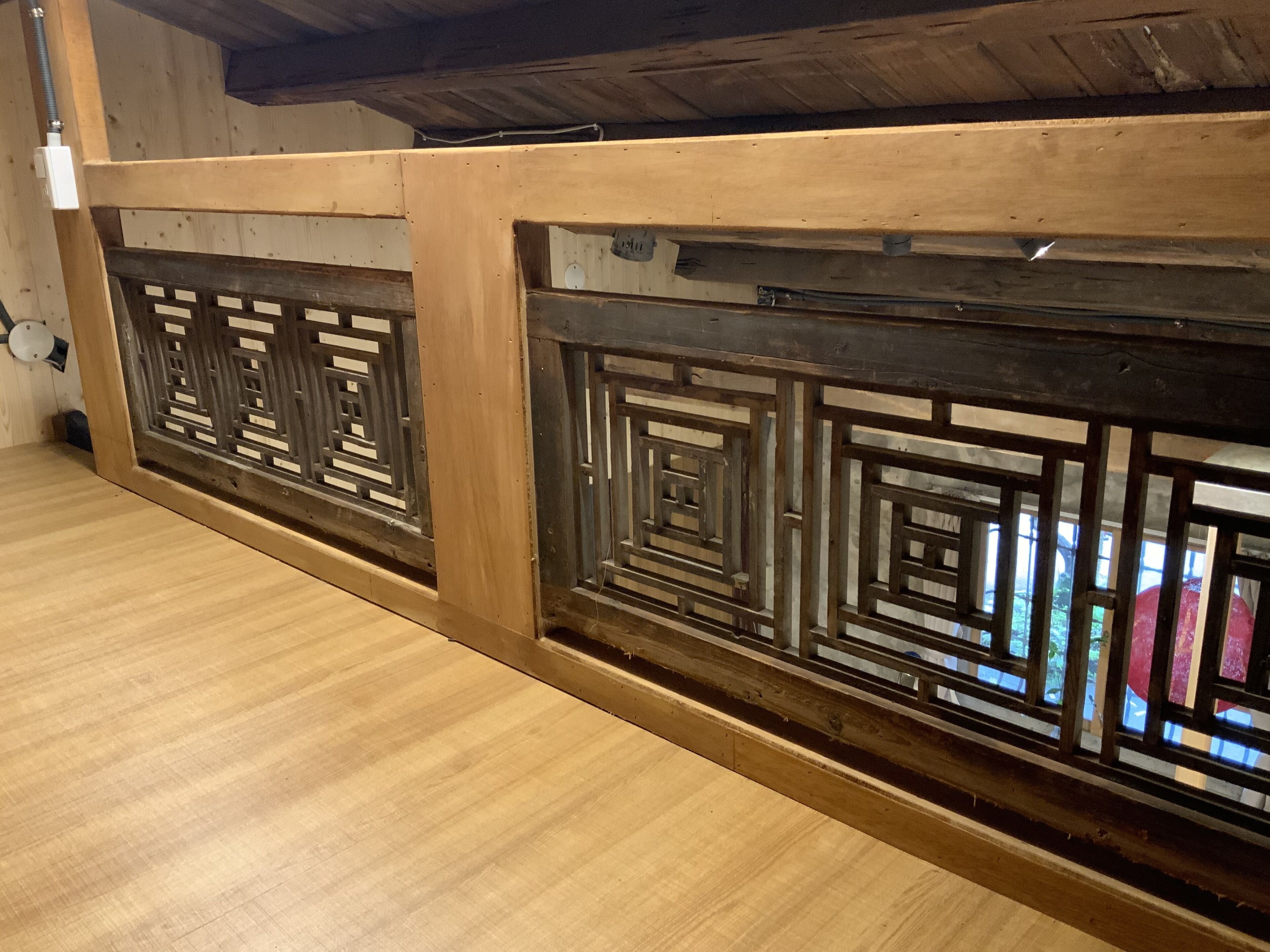 古意生活藝術館夾層邊的深色幾何木格、木樑與淺色地板。